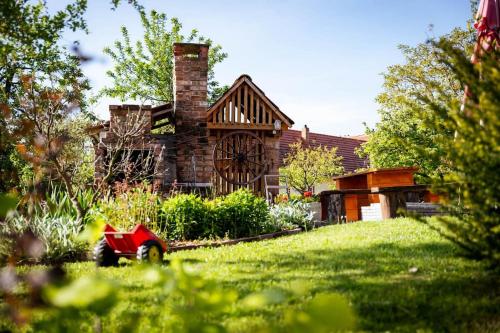 a house with a grassy yard with a red car in front at Rozmaring Vendégház in Zengővárkony