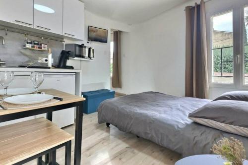 a bedroom with a bed and a table and a kitchen at Bleu Lavande 1 - Appartement cosy ambiance village in Istres