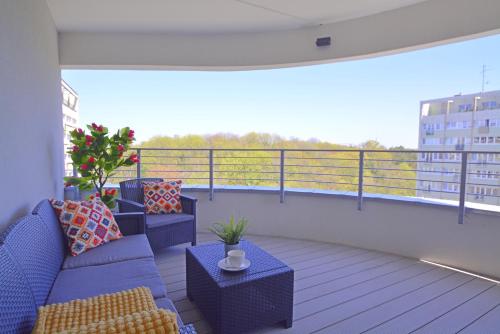 a balcony with a couch and tables on a balcony at Sun Towers - Apartamenty Bryza - Apartamenty z parkingiem in Świnoujście