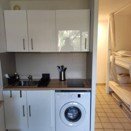 une cuisine avec une machine à laver et un évier dans l'établissement studio cabine quatre couchages classé 2 étoiles, à Bormes-les-Mimosas