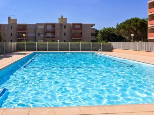 une grande piscine bleue avec des bâtiments en arrière-plan dans l'établissement studio cabine quatre couchages classé 2 étoiles, à Bormes-les-Mimosas