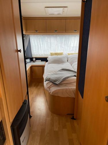 a small bed in a small room with a window at Cozy Caravan in Vestmannaeyjar