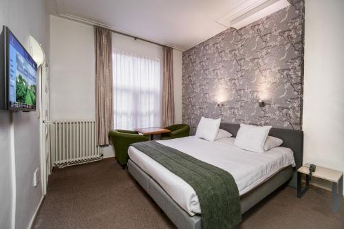 a hotel room with a bed and a tv at Hotel Bourgoensch Hof in Bruges