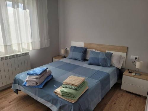 Un dormitorio con una cama azul con toallas. en Casa Julio, bonita casa reformada con terraza y jardin privado, en Riezu