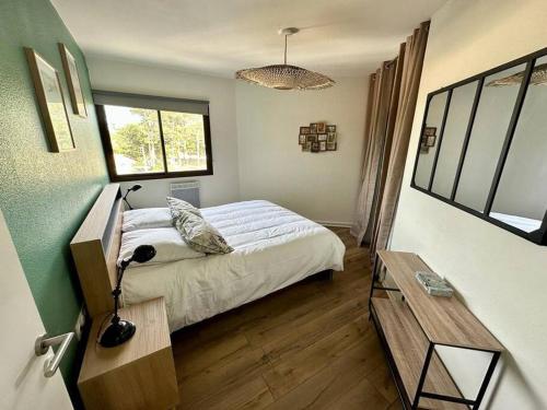 une chambre avec un lit, un bureau et une fenêtre dans l'établissement Green Oasis, à Biscarrosse