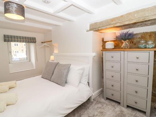 a bedroom with a white bed and a dresser at Hideaway Cottage in Barnoldswick