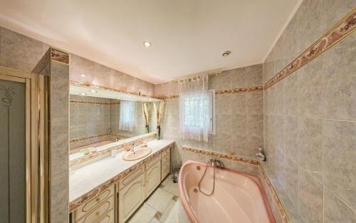 y baño con bañera rosa y lavamanos. en Maison provençale dans un cadre bucolique, en Grignan