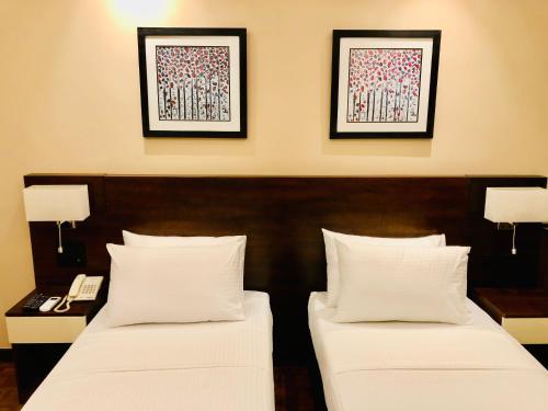 two beds in a hotel room with two pictures on the wall at Tropic Inn - Mount Lavinia in Mount Lavinia