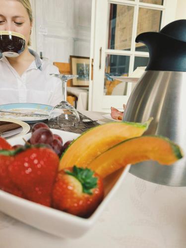 a woman sitting at a table with a plate of fruit at B&B Herenhuis1919 in Lo-Reninge