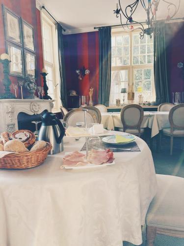 a white table with a basket of food on it at B&B Herenhuis1919 in Lo-Reninge