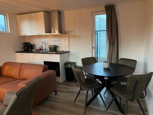 eine Küche und ein Wohnzimmer mit einem Tisch und einem Sofa in der Unterkunft Linked Chalet in Oostvoorne