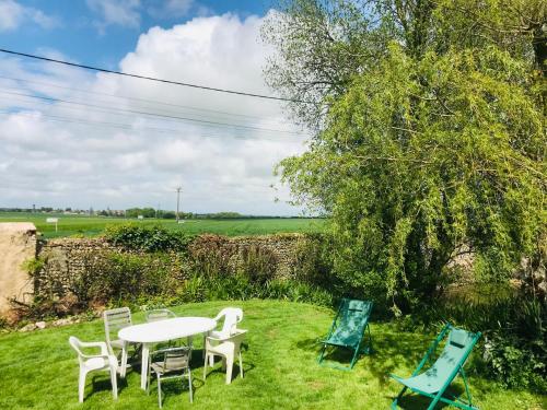 a table and chairs in the grass next to a tree at Gîte de la Perdrix 