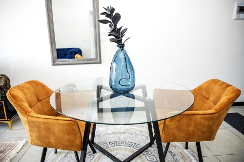 una mesa de cristal con dos sillas y un jarrón. en Eirini Elegant - Athena Apartment Fourways, en Sandton