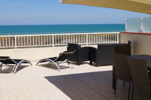 patio ze stołem i krzesłami oraz plażą w obiekcie Terrazza Azzurra w mieście Vasto