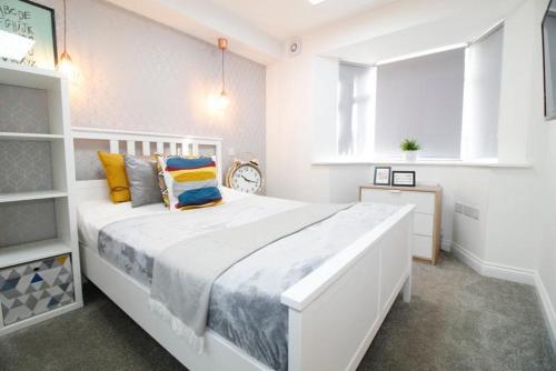 a white bedroom with a large white bed with colorful pillows at Leicester City Apartments in Leicester