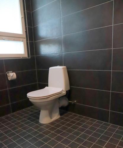 a bathroom with a toilet in a black tiled wall at Kassikäpa villa in Haapsalu