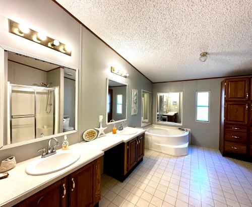 a bathroom with two sinks and a tub and a toilet at Orange Beach! Spacious mobile home near the beach! in Orange Beach