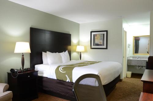 a hotel room with a large bed and a chair at Quality Inn & Suites Covington in Covington