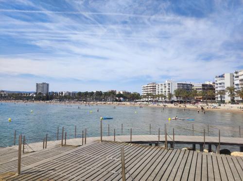 a beach with people in the water and buildings at Apartamentos CT in Salou