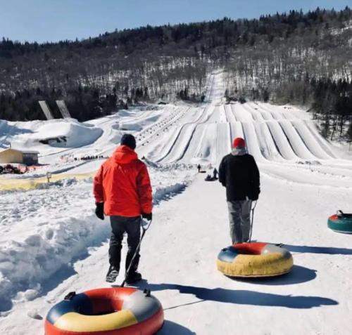 two men are standing in the snow next to tubing at Chalet 23 Chemin des Quarante by Les Chalets Alpins in Stoneham