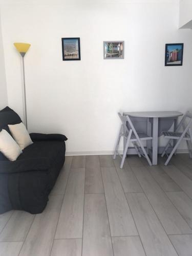 un salon avec un canapé noir et une table dans l'établissement MAISON SAINT PALAIS SUR MER, à Saint-Palais-sur-Mer