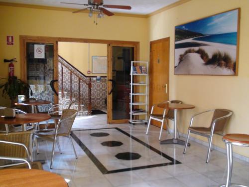 a dining room with tables and chairs and a staircase at Hostal Tarik in Tarifa