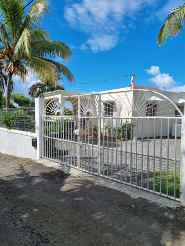 a white fence in front of a house with a palm tree at Le Soleil Villa in Centre de Flacq