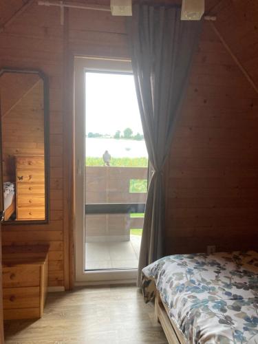 a bedroom with a bed and a sliding glass door at Bajkowa Przystań domki nad jeziorem in Żoń