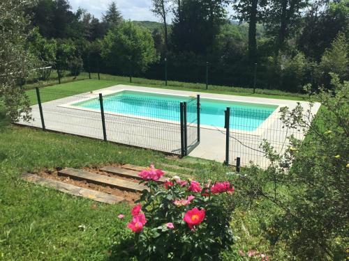 une piscine derrière une clôture avec des fleurs roses dans l'établissement Maison Perigord Noir Chez Daniela, à Carsac-Aillac