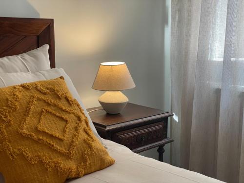 a bedroom with a bed with a lamp on a table at Quinta do Areal in Lousã