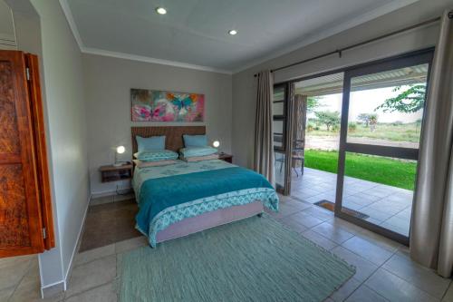 een slaapkamer met een bed en een glazen schuifdeur bij Khoi-Khoi Guesthouse in Otavi