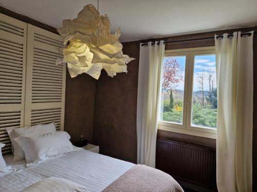 une chambre avec un lit, une fenêtre et un lustre dans l'établissement Maison Perigord Noir Chez Daniela, à Carsac-Aillac