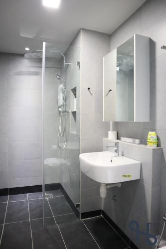 a bathroom with a white sink and a shower at Homesuite' Home at Jesselton Quay in Kota Kinabalu