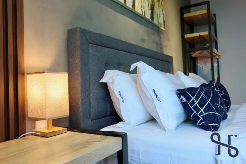 a bed with white pillows and a table with a lamp at Homesuite' Home at Jesselton Quay in Kota Kinabalu