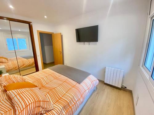 a bedroom with a bed and a tv on the wall at Coast apartment near Barcelona in Sant Andreu de Llavaneres