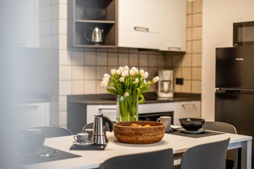 a vase of flowers on a table in a kitchen at Appartamenti Vasco Renna Surf Center in Nago-Torbole