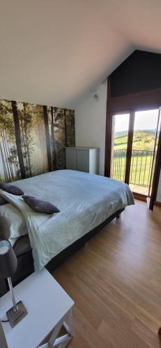 a bedroom with a large bed and a large window at La Cabra Trepadora in Neril