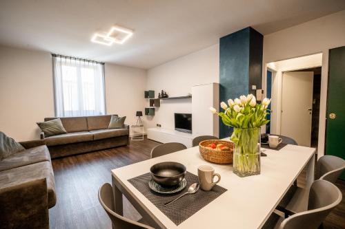 a living room with a table with a vase of flowers at Appartamenti Vasco Renna Surf Center in Nago-Torbole
