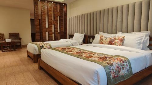 a bedroom with two beds with white sheets at Mount Polaris Suites & Spa in Kalimpong