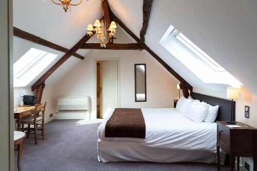 a bedroom with a bed and a desk in a attic at Hôtel Grand Monarque in Azay-le-Rideau