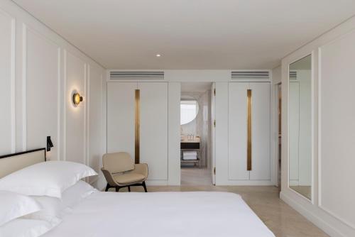 a white bedroom with a bed and a chair at Theatron Jerusalem Hotel & Spa - MGallery Collection in Jerusalem