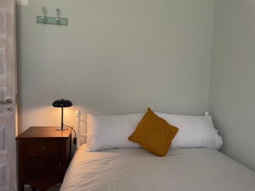 a bed with white sheets and a yellow pillow on it at Quinta do Areal in Lousã