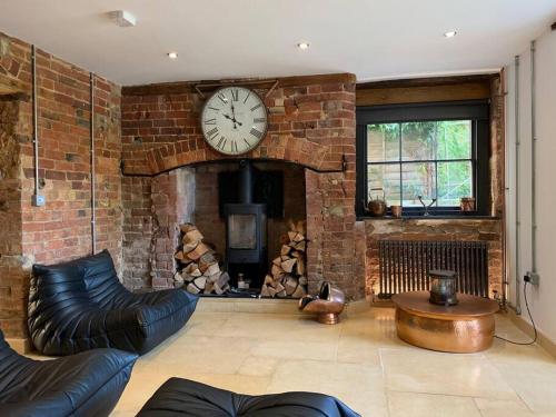 a living room with a brick wall with a clock at Lavish Apartment at Montpellier Gardens in Cheltenham