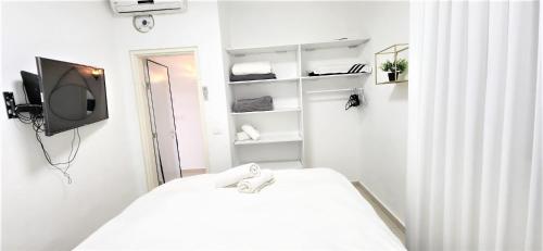Dieses weiße Zimmer verfügt über ein Bett und einen TV. in der Unterkunft sea view & pool eilat in Eilat