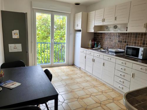 une cuisine avec des armoires blanches et une table dans l'établissement Maison de ville avec 4 grandes chambres, à Brest