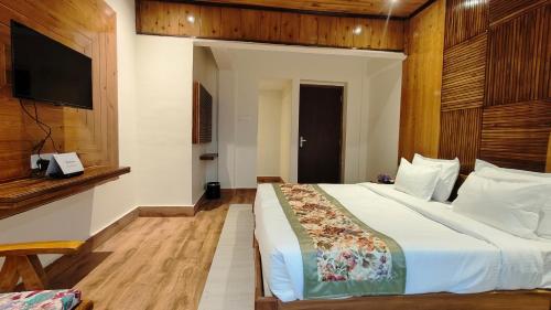 a bedroom with a large bed and a television at Mount Polaris Suites & Spa in Kalimpong