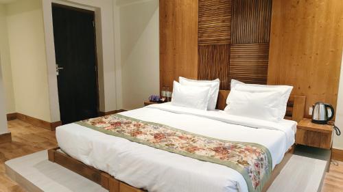 a bedroom with a large bed with white sheets at Mount Polaris Suites & Spa in Kalimpong