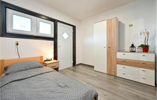 a bedroom with a bed and a dresser and windows at Gorgeous Home In Jalsje With Sauna in Martinišće
