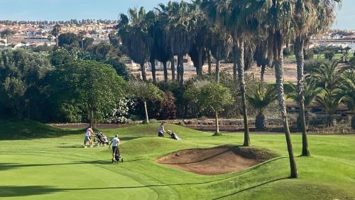 a group of people playing golf on a golf course at Sunny Luxury Apartment with two-level terrace, two swimming pools, next to golf course in Caleta De Fuste