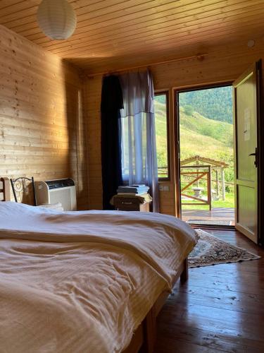 a bedroom with a large bed and a large window at B & B Juta in Kazbegi